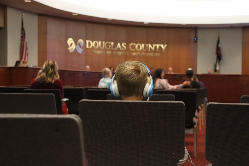 A boy listens to his headphones as Douglas County Health Board members debate allowing students and teachers to opt out of masking mandates in schools at an Oct. 8 special meeting.